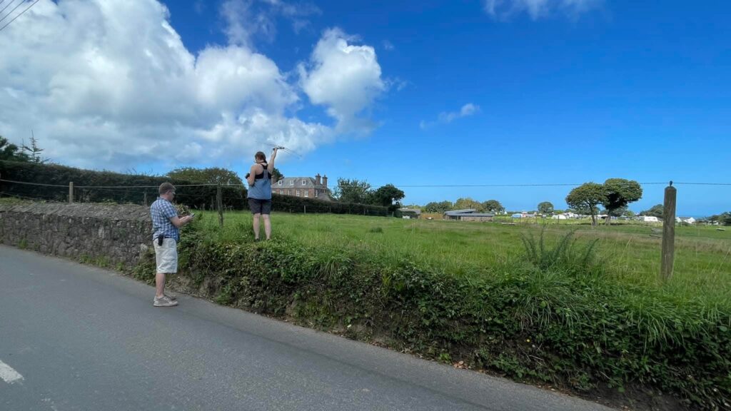 People taking photos by grassy field and blue sky.