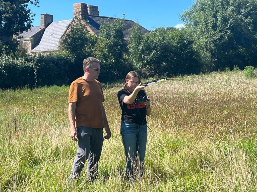 Two people surveying field with instrument
