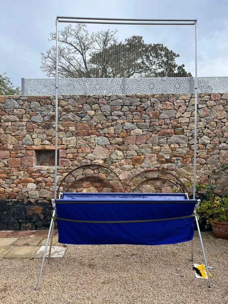 Solar water heater against stone wall and garden.