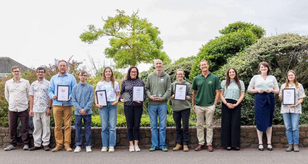 Group holding awards in garden setting.