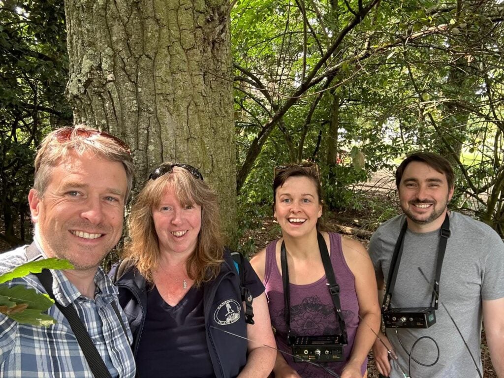 Group in forest smiles for selfie.