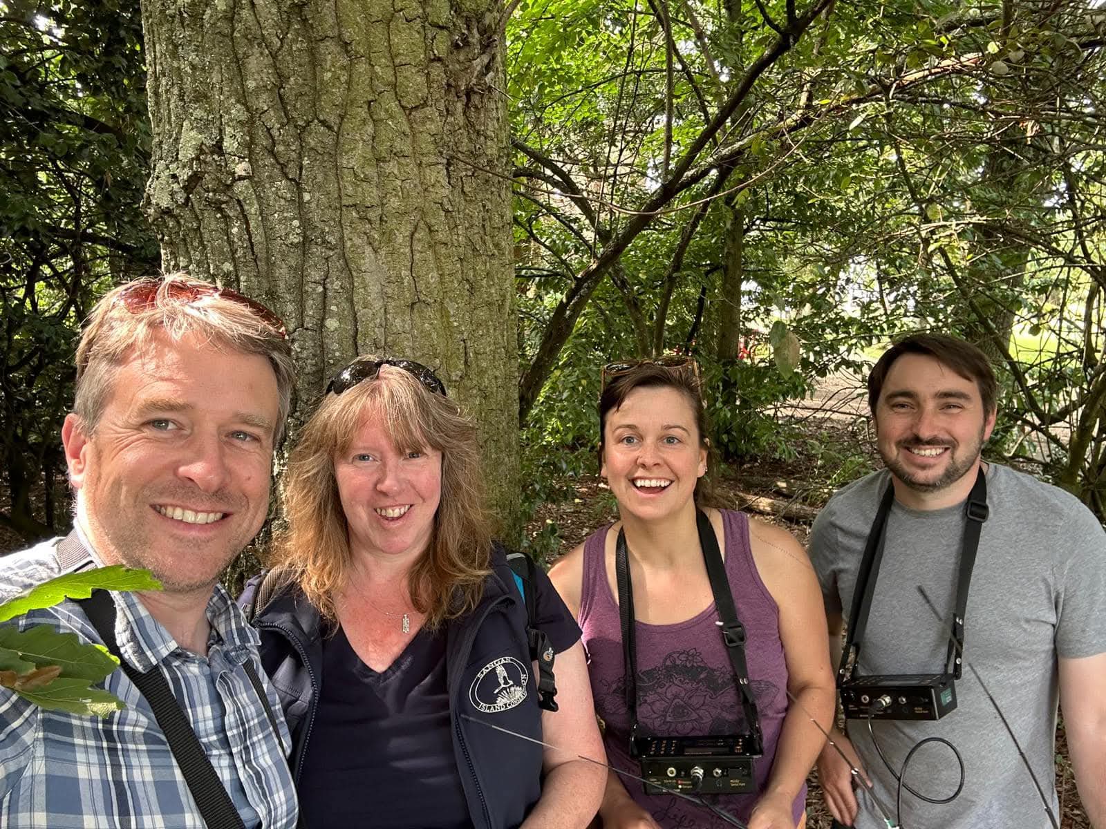 Group in forest smiles for selfie.