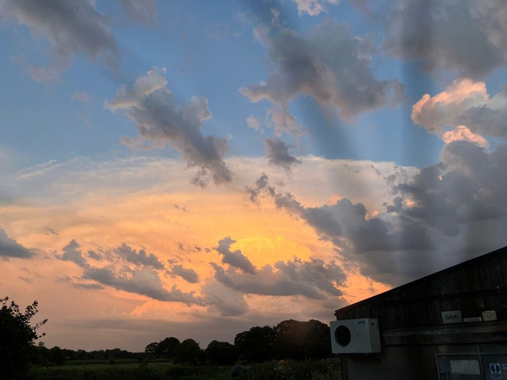 Colorful sunset sky with scattered clouds over landscape.