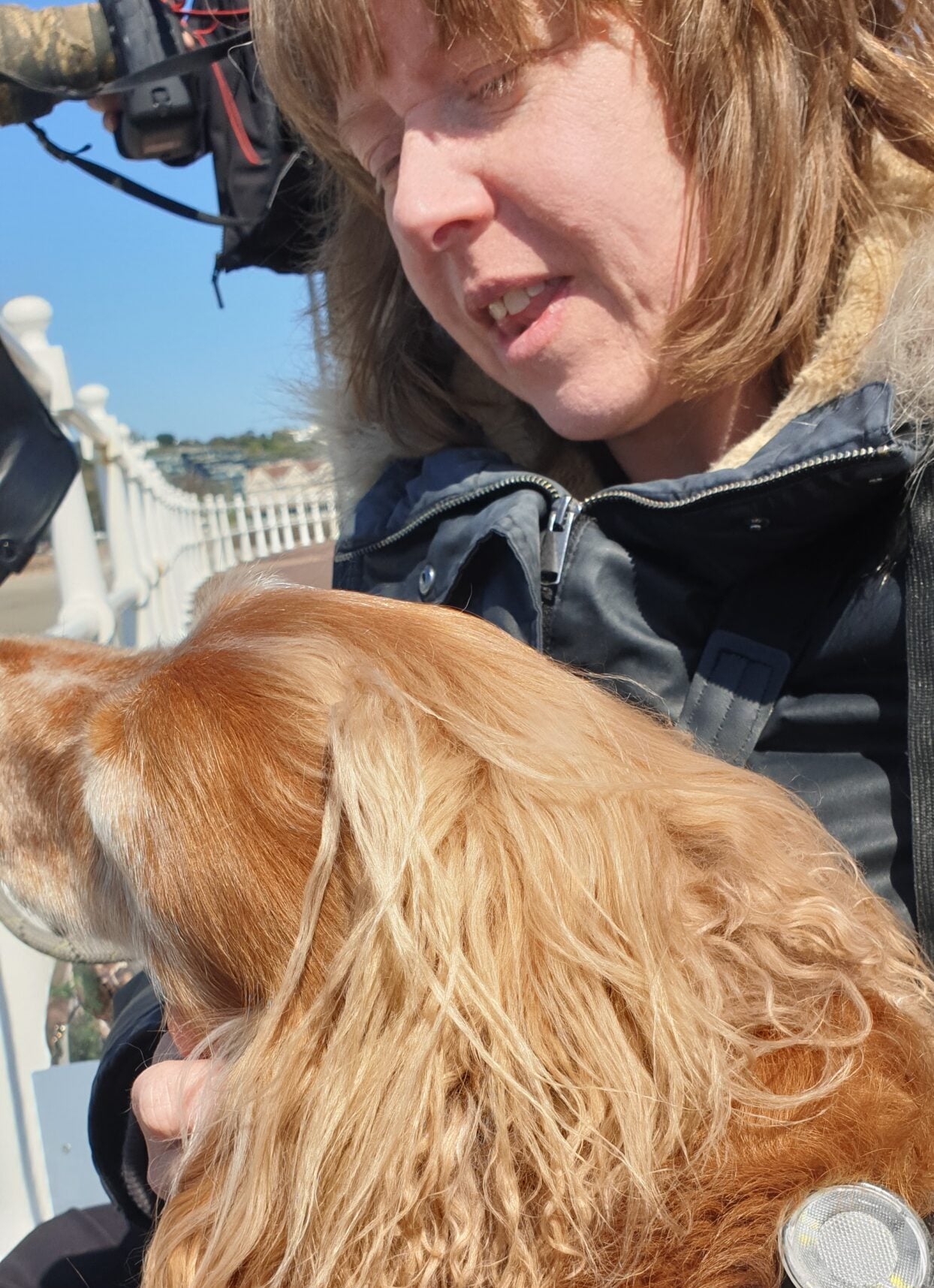 Woman with golden dog outdoors on sunny day.