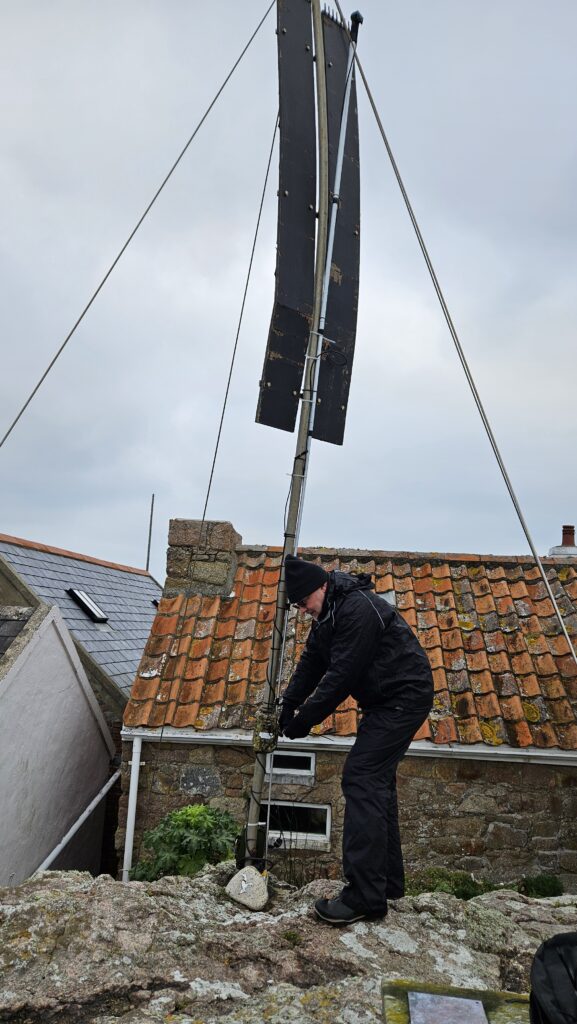 Person adjusting rooftop wind turbine on a house.