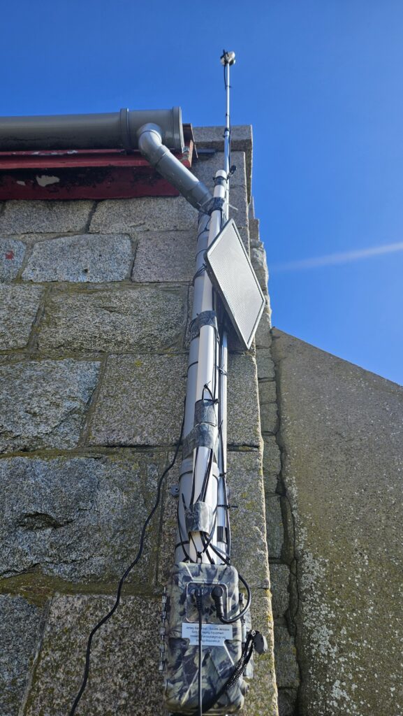 Mounted satellite dish on stone building wall.