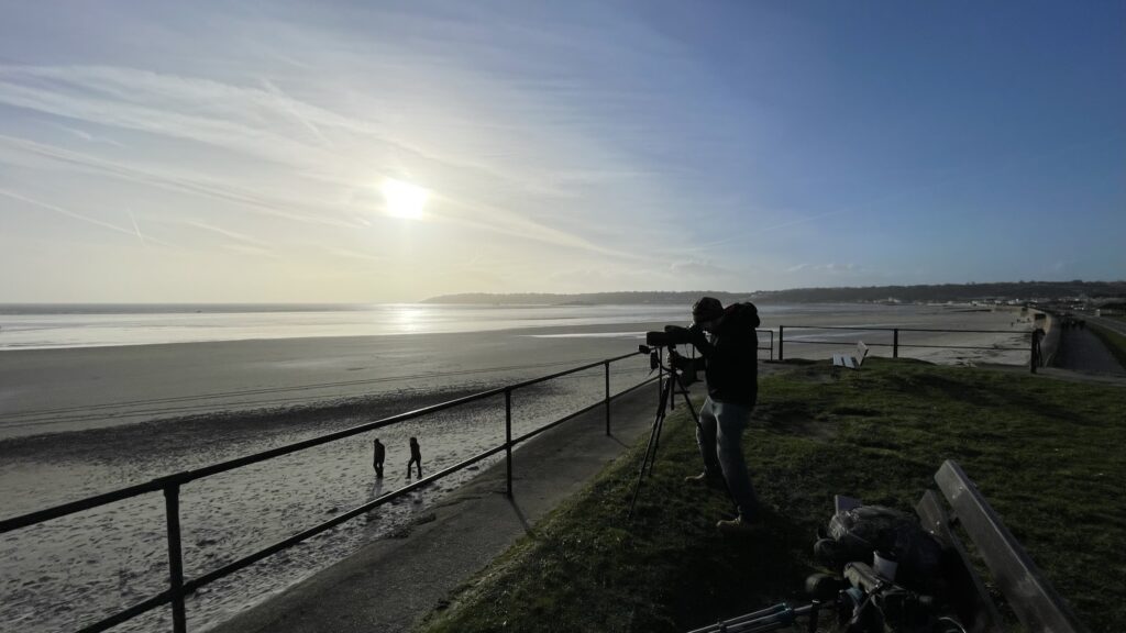 Person photographing beach at sunset