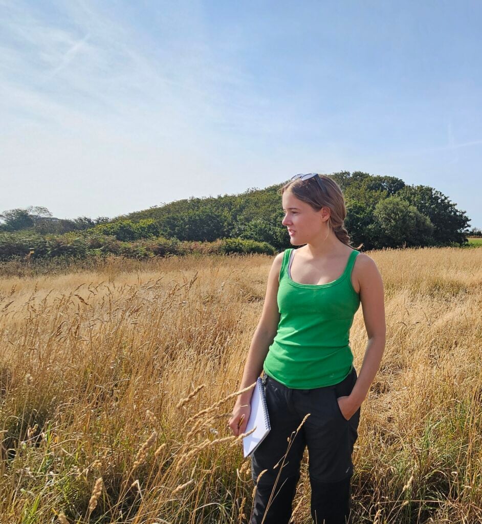 Woman in green top stands in a field.